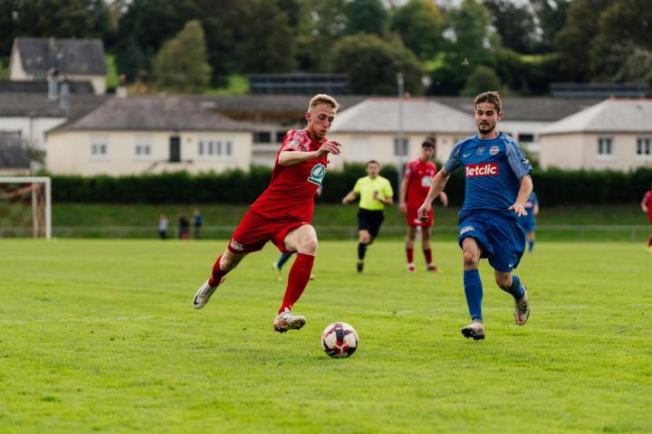 Action shot of soccer players competing on a lush green field outdoors.