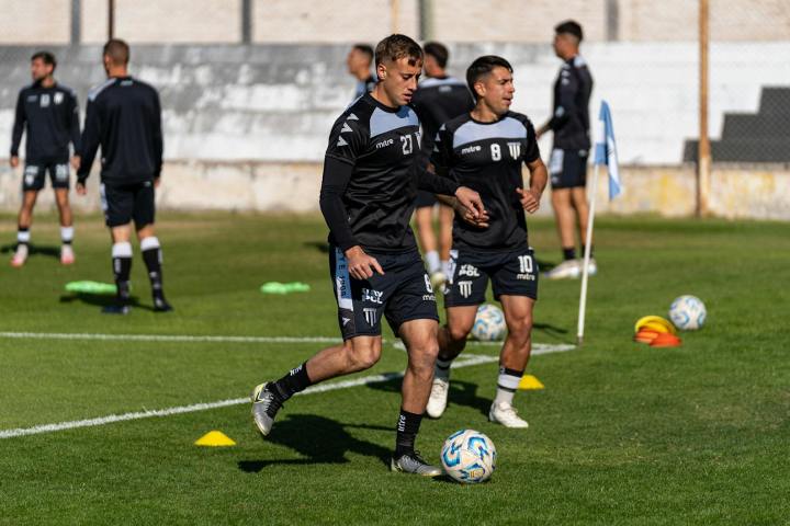 Group of young football players practicing on a sunny field, showcasing teamwork and skill development.