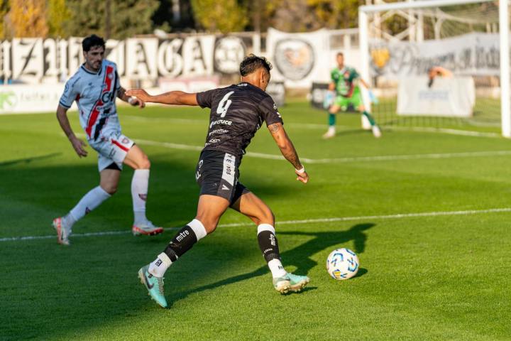 Football players in intense action on a sunny day match in an outdoor stadium.