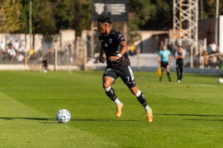 Soccer player dribbling the ball during a daytime match outdoors.