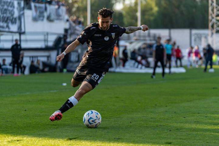Dynamic action shot of a footballer kicking the ball on the field during a match.